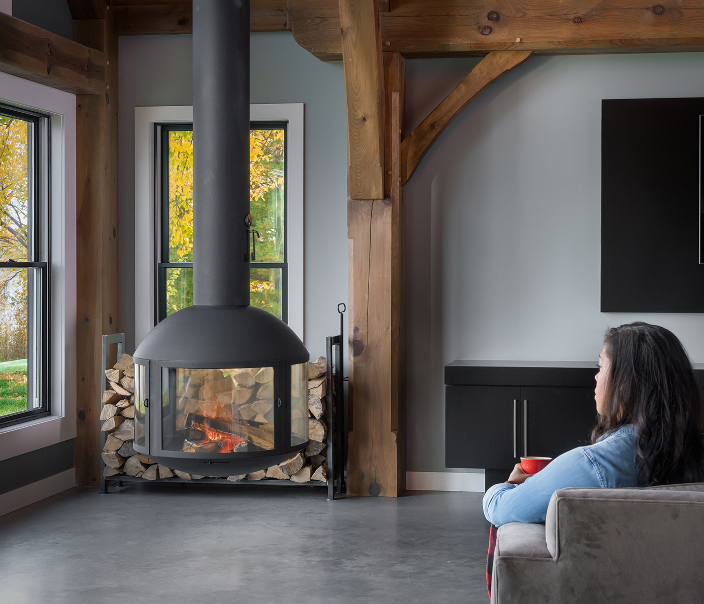 Woman seated in her living room next to a suspended wood burning stove